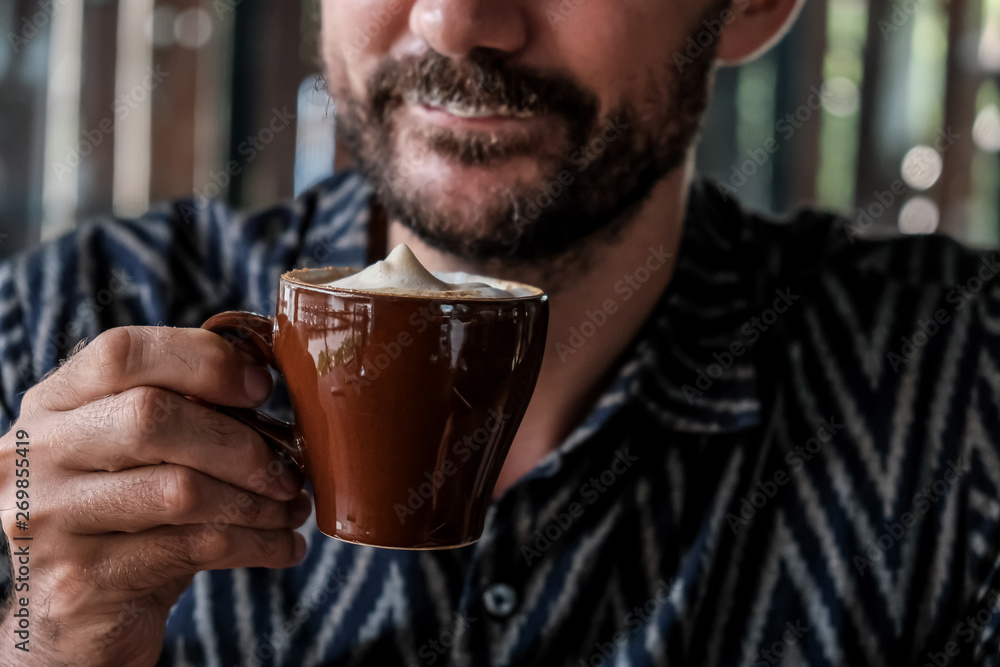 Young man enjoying cappuccino or latte coffee in a cafe Young man enjoying cappuccino or latte coffee in a cafe