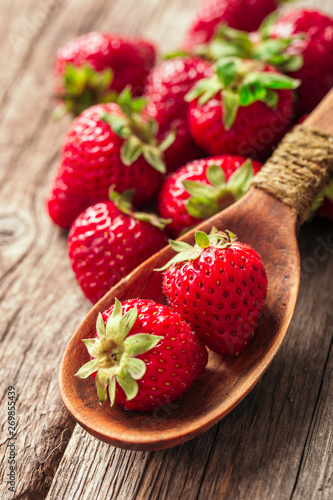 Freshly picked Strawberry in spoon on wooden background. Healthy eating and nutrition.