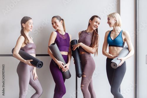 Four beautiful slim positive young girls fitness models are preparing for joint training and rejoice at the meeting. The concept of sports lifestyle and like-minded people. Yoga concept