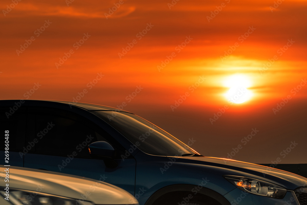 Side view of blue SUV car with sport and modern design parked on concrete road at sunset. Hybrid and electric car technology. Road trip. Automotive industry. Car parking lot with beautiful sunset.