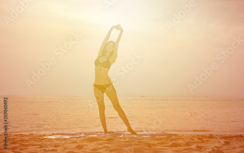 Fototapeta Naklejka Na Ścianę i Meble -  Slip women with Bikini standing warm up body on beach with sunray