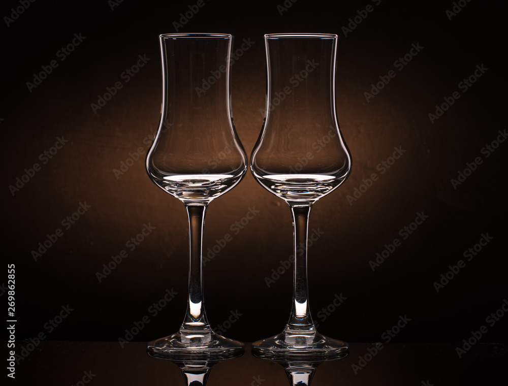 Two glasses of cognac sniffer on a colored dark background