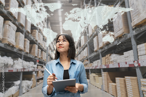 Young attractive asian manager woman looking, picking, replemishment, receiving inventory at store warehouse in warehouse management system concept. Smart ERP with iot for inventory management.