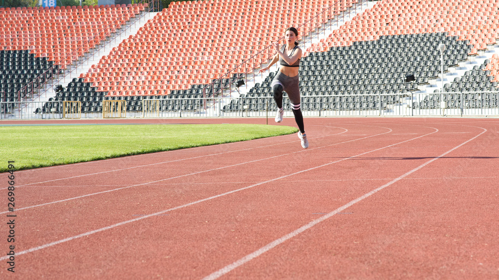 Fototapeta premium Beautiful athletic girl running around the stadium