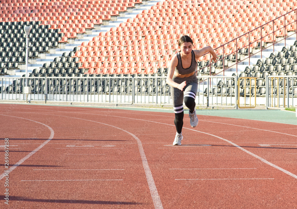 Fototapeta premium Beautiful athletic girl running around the stadium
