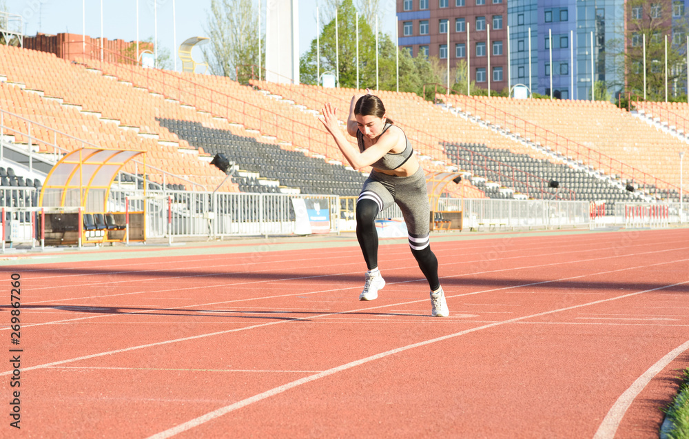 Fototapeta premium Beautiful athletic girl running around the stadium