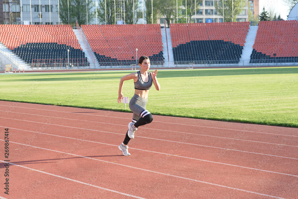 Fototapeta premium Piękna dziewczyna lekkoatletycznego biegania po stadionie