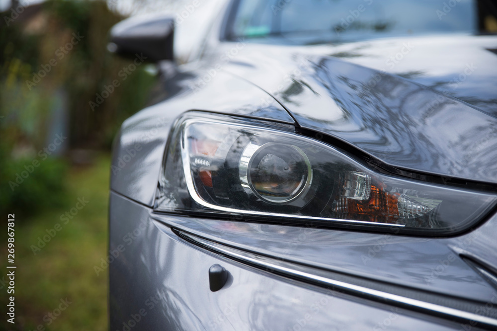 Close-up of the headlight of a grey car