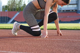 Young beautiful woman runner outdoor standing in start pose at the stadium