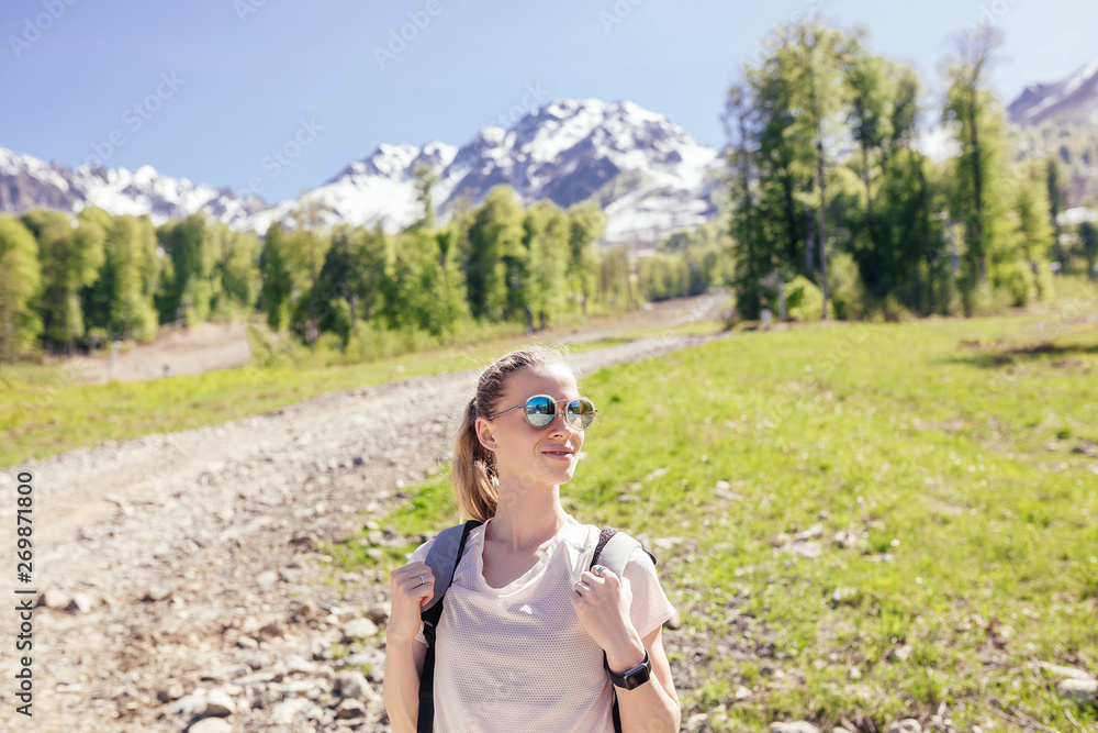 Naklejka premium Portrait of a beautiful slim young woman traveling alone in the mountains on a sunny warm day. Concept of a strong independent woman who is not afraid of difficulties and new discoveries