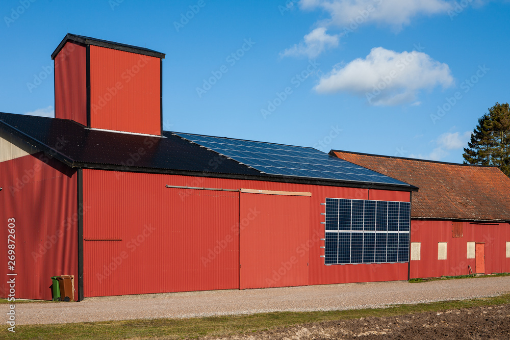 Obraz premium A farm in Sweden has added solar panels to the roof and wall of a barn building as a source of electricity.