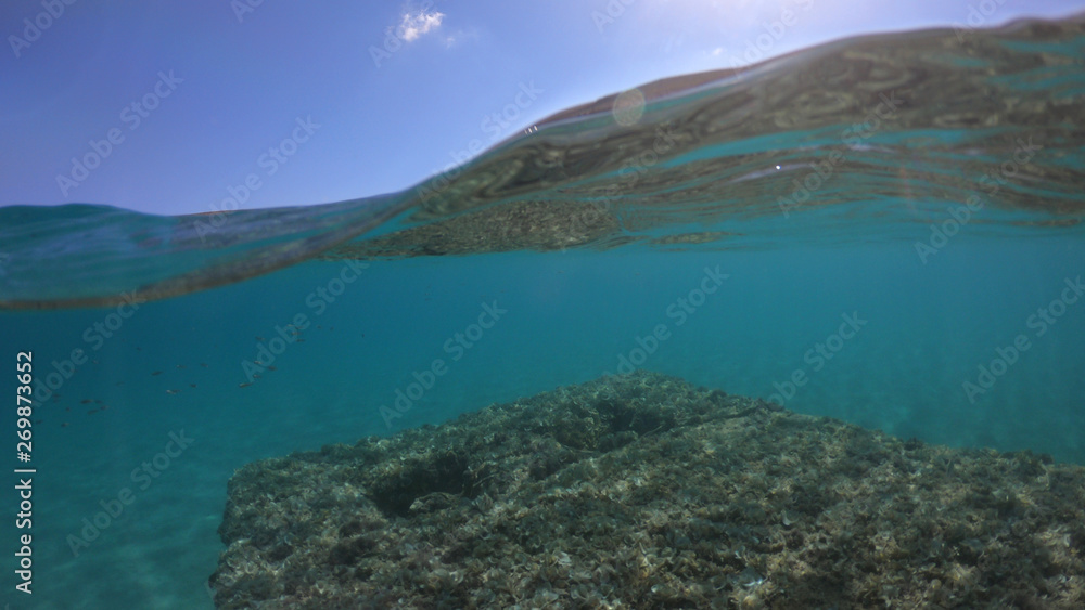 Fototapeta premium Underwater sea level photo of idilic pebble beach of Karavostasis, picturesque port of Folegandros island with traditional fishing boats docked and crystal clear turquoise sea, Cyclades, Greece