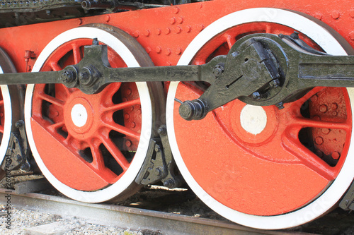 Red iron wheels of steam locomotive on rails close up