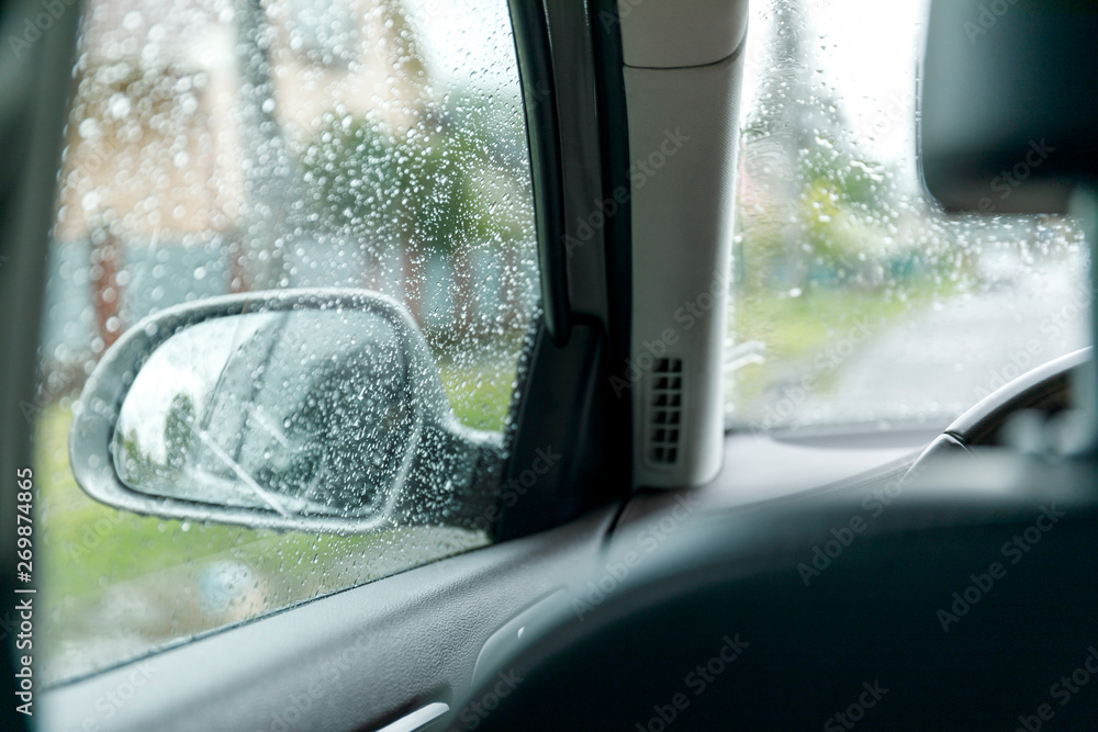 Fototapeta premium Side rear view mirror on a car. Reflection of rainy day at the car side mirrow.