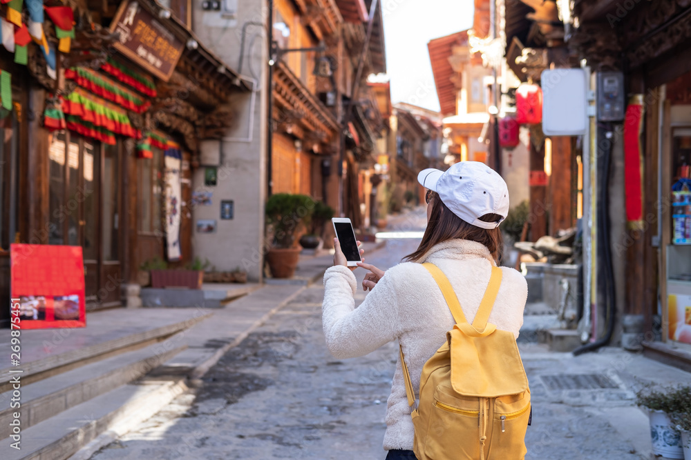 Young woman traveler walking in the old town, Shangri-la and using smartphone for searching location, Travel lifestyle concept