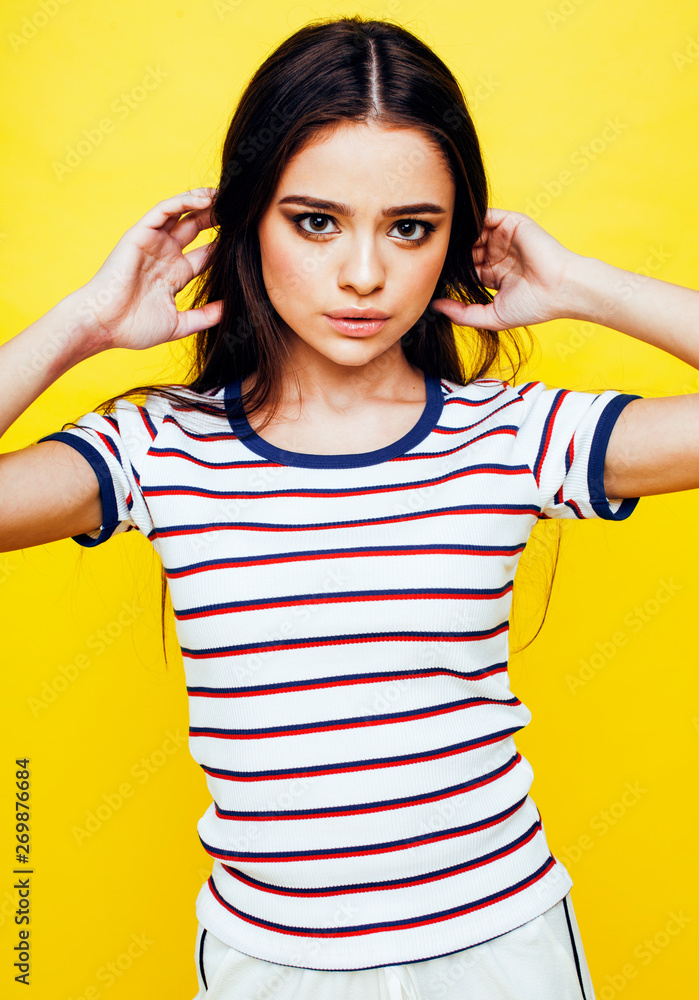 lifestyle people concept: pretty young school teenage girl having fun happy smiling on yellow background closeup lifestyle people concept: pretty young school teenage girl having fun happy smiling on yellow background closeup