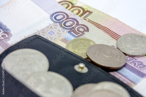 Russian paper money and a scattering of metal coins of different denominations on them a close-up on a black background. photo