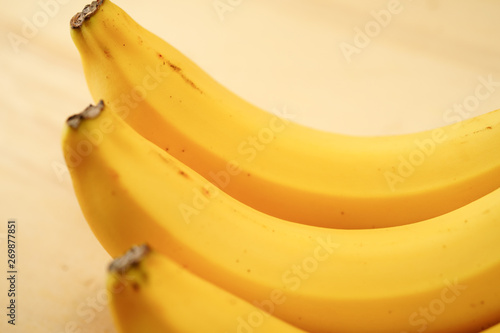 Three fresh and ripe yellow banana on a wooden base