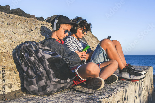 Happy fashion friends watching videos on smartphone. Beautiful boys having fun with social story app new trends technology Friendship youth lifestyle  millennials generation activity and tech concept