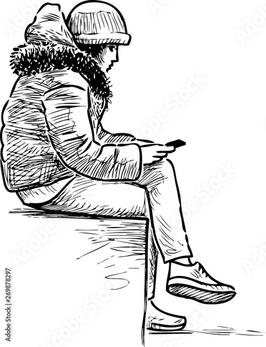 A teen girl sits on a street bench with her mobile phone