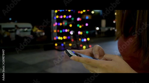 Woman use smart phone beside road, night city background