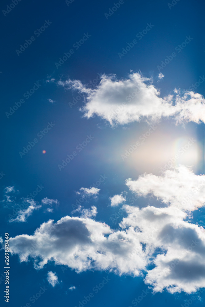 Lens Flare On Wispy Clouds in Vibrant, Deep Blue Sky Lens Flare On Wispy Clouds in Vibrant, Deep Blue Sky