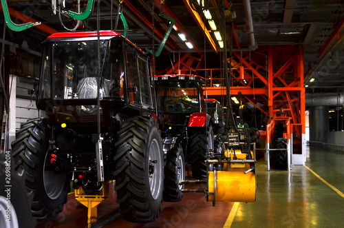 Tractor Manufacture work. Assembly line inside the agricultural machinery factory. Installation of parts on the tractor body - Image © MaxSafaniuk