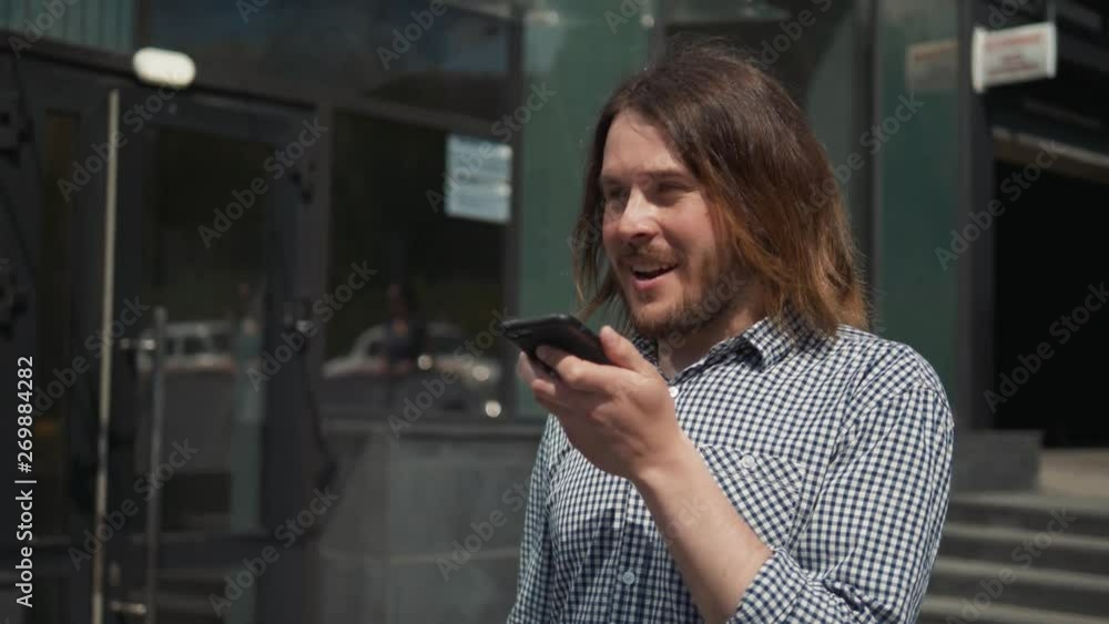 Man using the voice recognition on the phone, audio message ai speech helper, student male outdoor Man using the voice recognition on the phone, audio message ai speech helper, student male outdoor