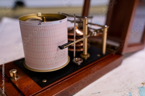 Vintage marine barograph with opened cover standing on a navigational chart