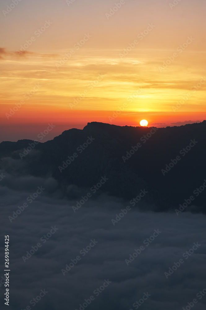 beautiful sunset above the clouds in the mountains. stunned landscape background with copy space. aerial mountain view. vertical	