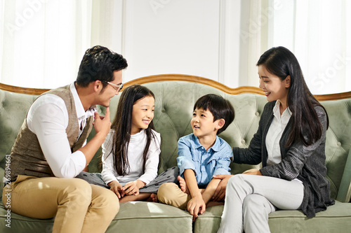 asian parents and two children chatting at home