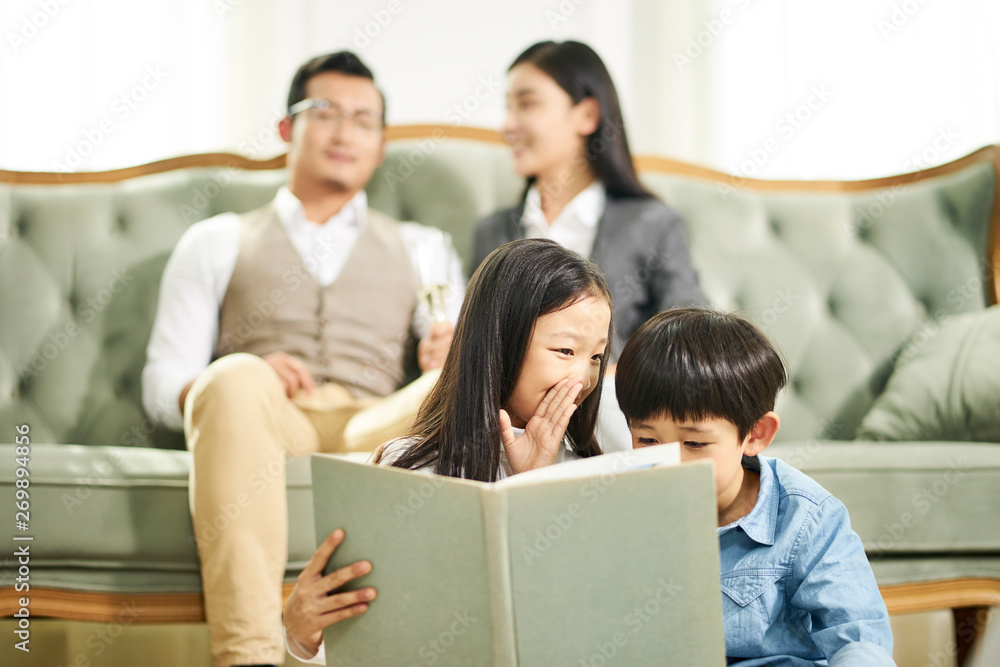 two asian children reading book together