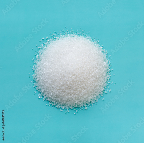 heap of sugar in the shape of a circle on a blue background, macro