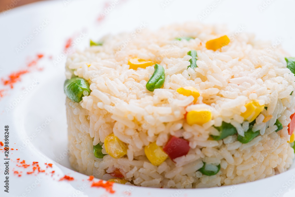 boiled rice with vegetables in a white plate on a wooden table boiled rice with vegetables in a white plate on a wooden table