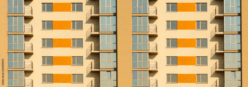 Wide fragment of symmetric exterior of modern multi apartment residential building.