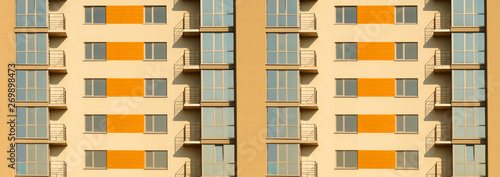 Wide fragment of symmetric exterior of modern multi apartment residential building.