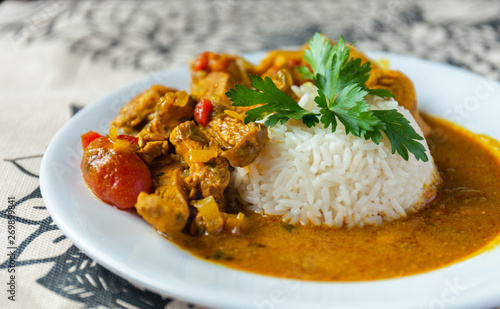 Curry chicken bright juicy with white rice on plate over the tablecloth background. side view.