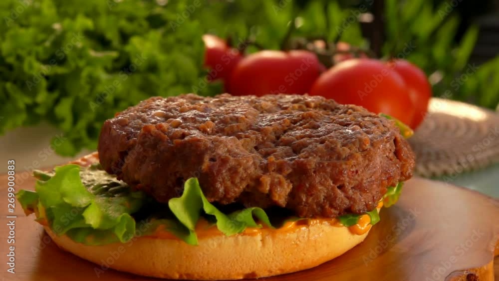 Ready cutlet falls on a hamburger with sauce and a leaf of lettuce. On the table prepared products for burgers Ready cutlet falls on a hamburger with sauce and a leaf of lettuce. On the table prepared products for burgers