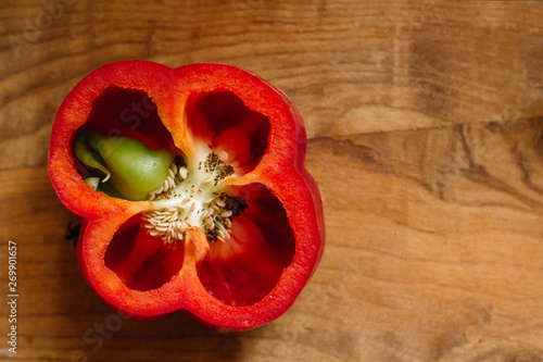 Fresh sweet red pepper cut in half with a growth inside on old wooden background. Overgrown boot