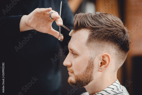 Barbershop, man barber in men hairdresser does hair with scissors