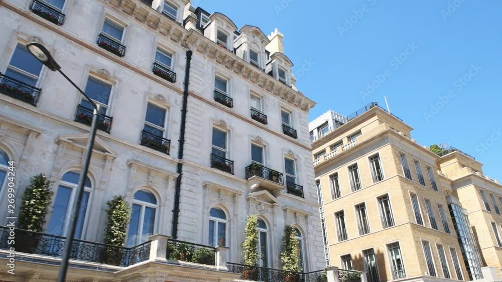 Low angle looking up point of view pov driving on car with panning on Grosvenor Place street with old historic architecture of terraced row houses against blue summer  sky in Belgravia, London, UK