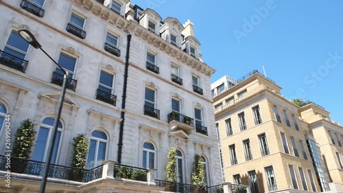 Low angle looking up point of view pov driving on car with panning on Grosvenor Place street with old historic architecture of terraced row houses against blue summer  sky in Belgravia, London, UK