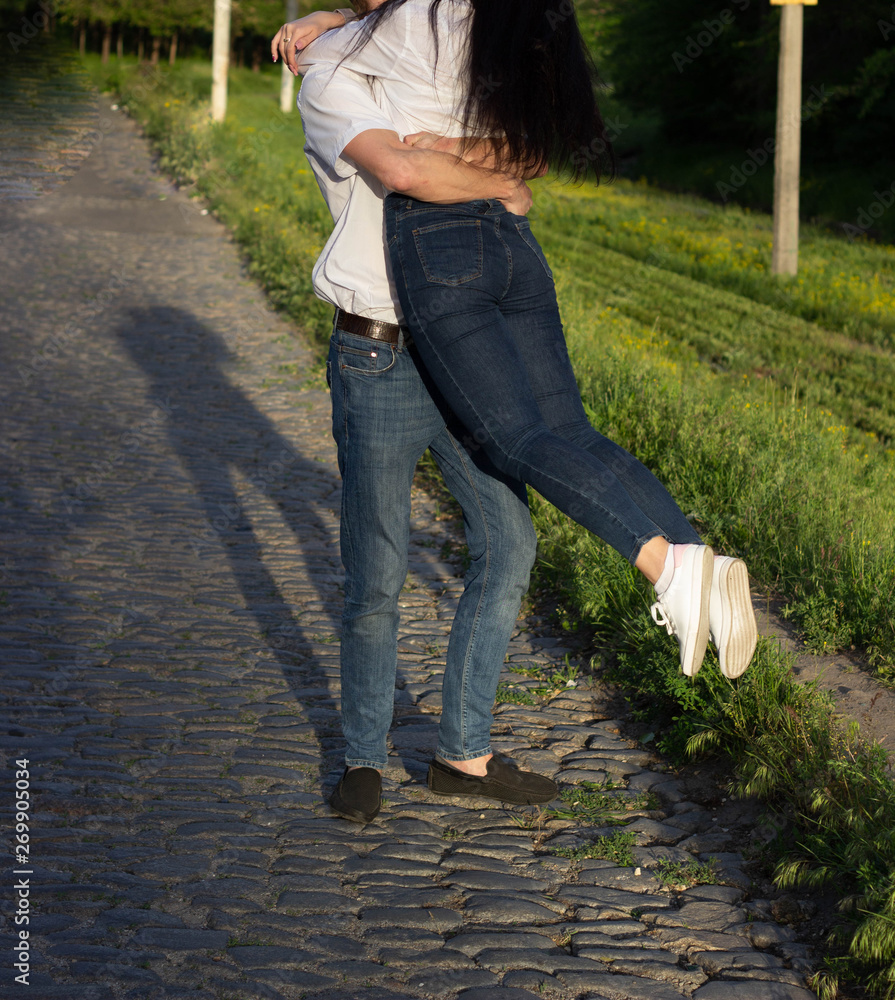 Fototapeta premium Happy couple in love hugging and kissing while walking in the park