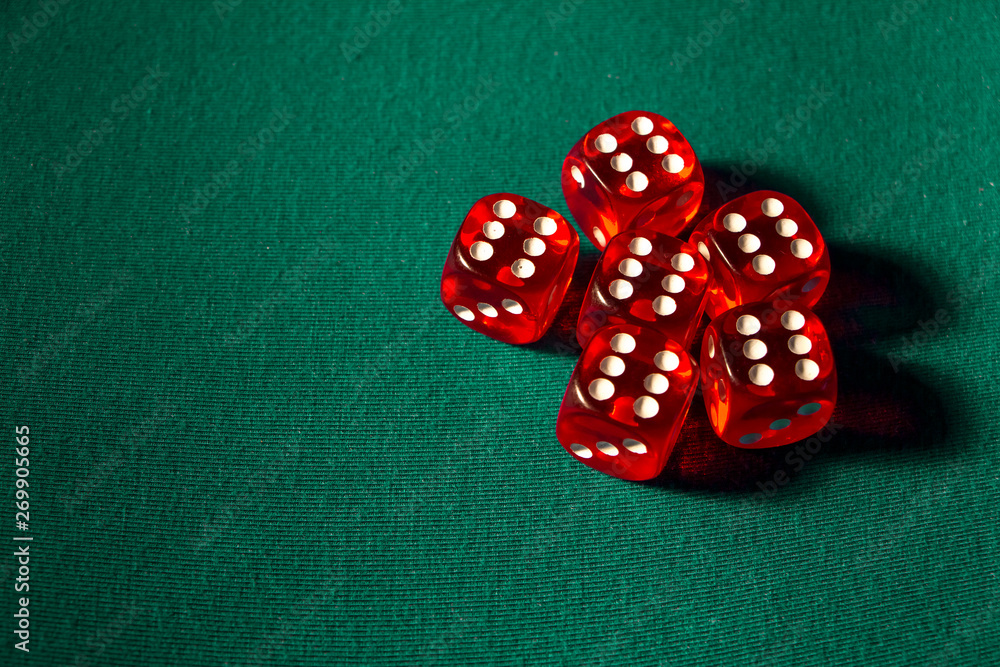 Close-up of several red dice with different digital combinations on green cloth in a casino Close-up of several red dice with different digital combinations on green cloth in a casino