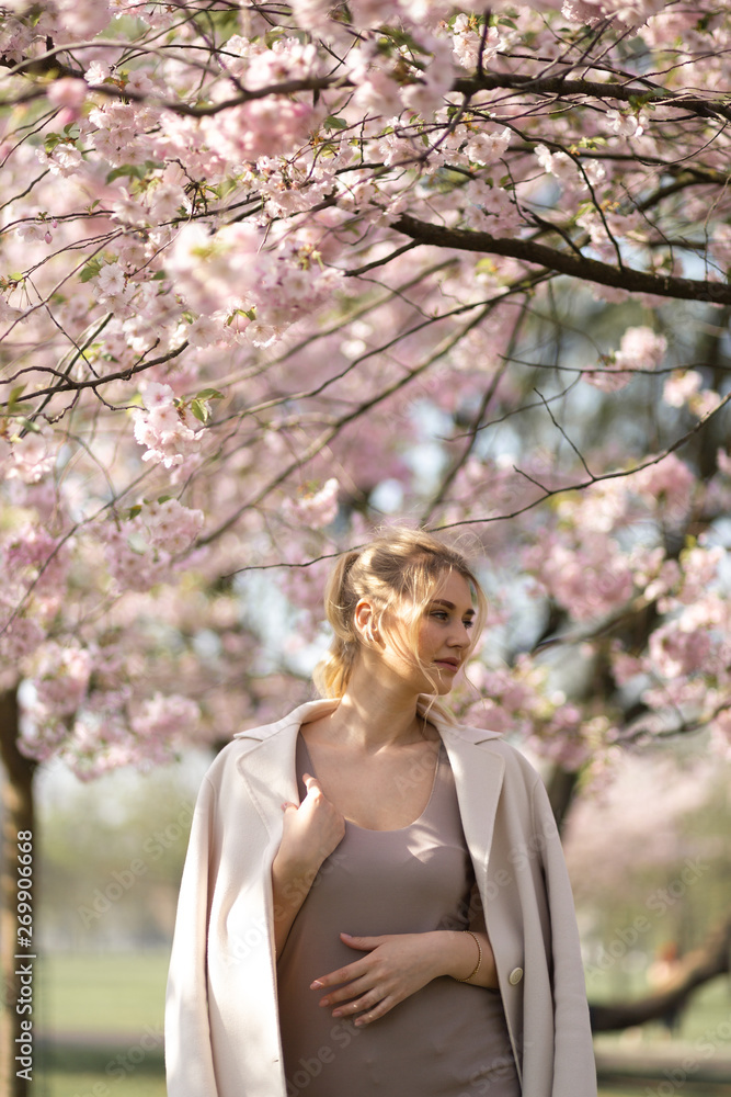 Beautiful blonde young woman in Sakura Cherry Blossom park in Spring enjoying nature and free time during her traveling tourist free time - Wearing white pants and t-shirt with a beige jacket Beautiful blonde young woman in Sakura Cherry Blossom park in Spring enjoying nature and free time during her traveling tourist free time - Wearing white pants and t-shirt with a beige jacket