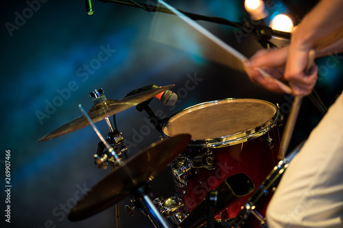 The man is playing drum set, low light background