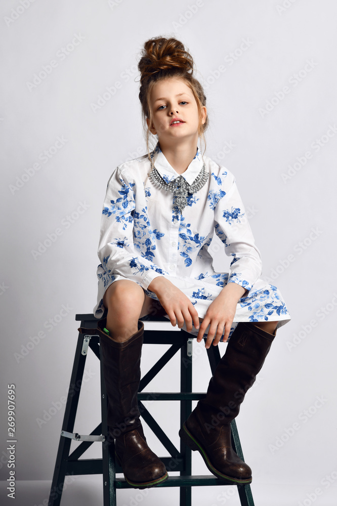 Pretty fashionable kid girl teenager in modern dress and high boots is  sitting on black stepladder Photos | Adobe Stock