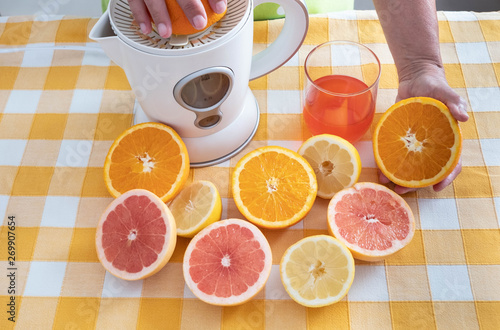 Glass of fresh orange and grapefuit juice made with squeezer and natural fresh fruits. Yellow checkered tableclock. Break of breakfast time photo