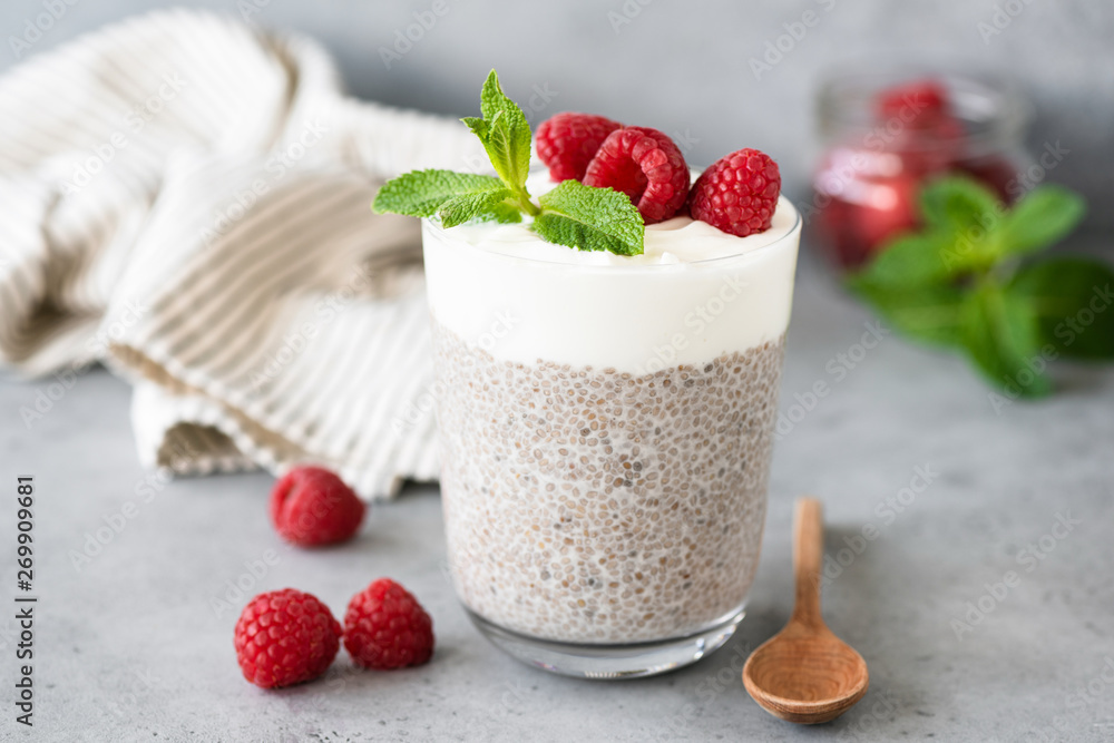 Vegetarian chia pudding with yogurt and raspberries in glass on concrete table. Healthy lifestyle, healthy eating, weight loss, fitness menu food Vegetarian chia pudding with yogurt and raspberries in glass on concrete table. Healthy lifestyle, healthy eating, weight loss, fitness menu food