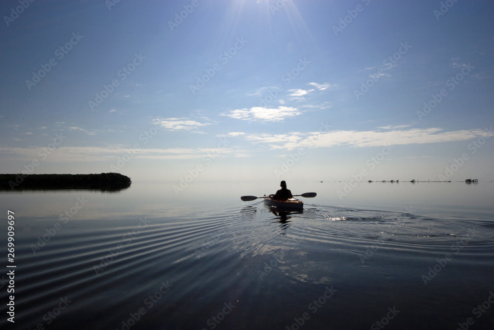 Kayaker enjoying a very calm early morning paddle on Biscayne Bay in Biscayne National Park, Florida